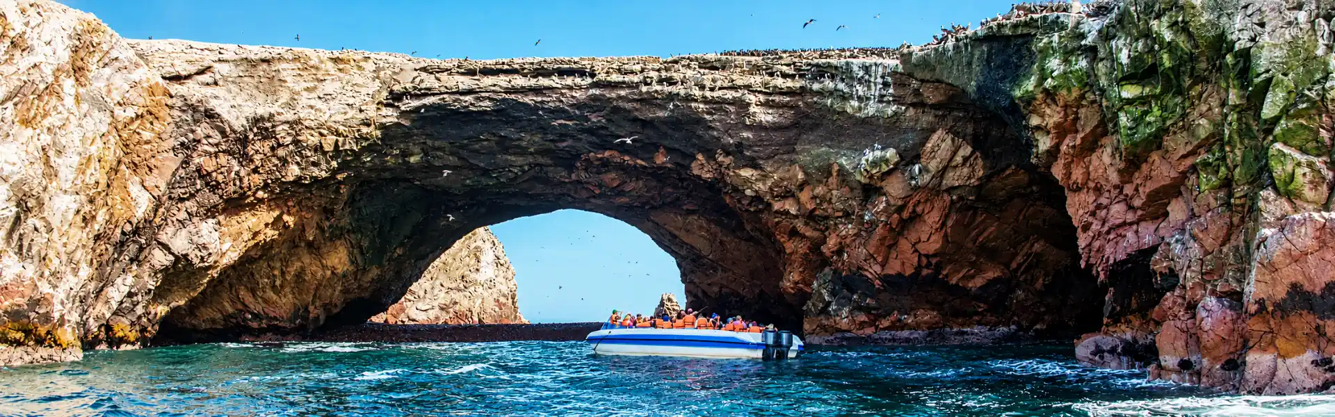 Bote turístico frente a un arco de roca