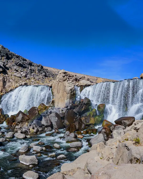 Cascada de Pillones rodeada de rocas en paisaje andino de altura en Perú