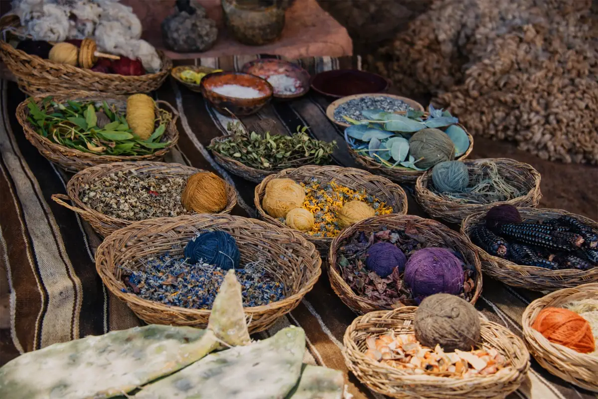 Canastas con tintes naturales y lanas teñidas: hojas, flores, cochinilla y madejas de colores para el tejido tradicional.