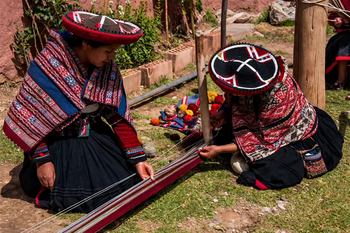 Artesanas de Chinchero preparando el telar y tensando los hilos en el suelo para iniciar el tejido andino.