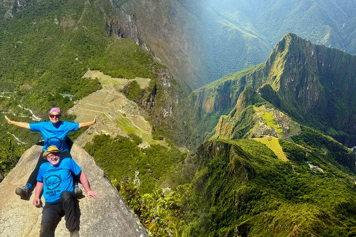 Viajeros en la cima de Huayna Picchu con vista panorámica de Machu Picchu y las montañas andinas
