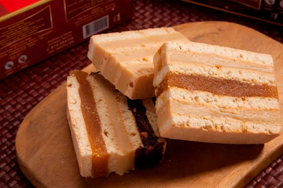 King kong peruano en porciones, con capas de galleta y relleno de manjar blanco y dulce, servido sobre tabla de madera.