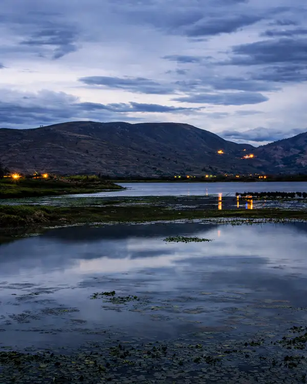 Laguna de Paca al atardecer con colinas y cielo nublado