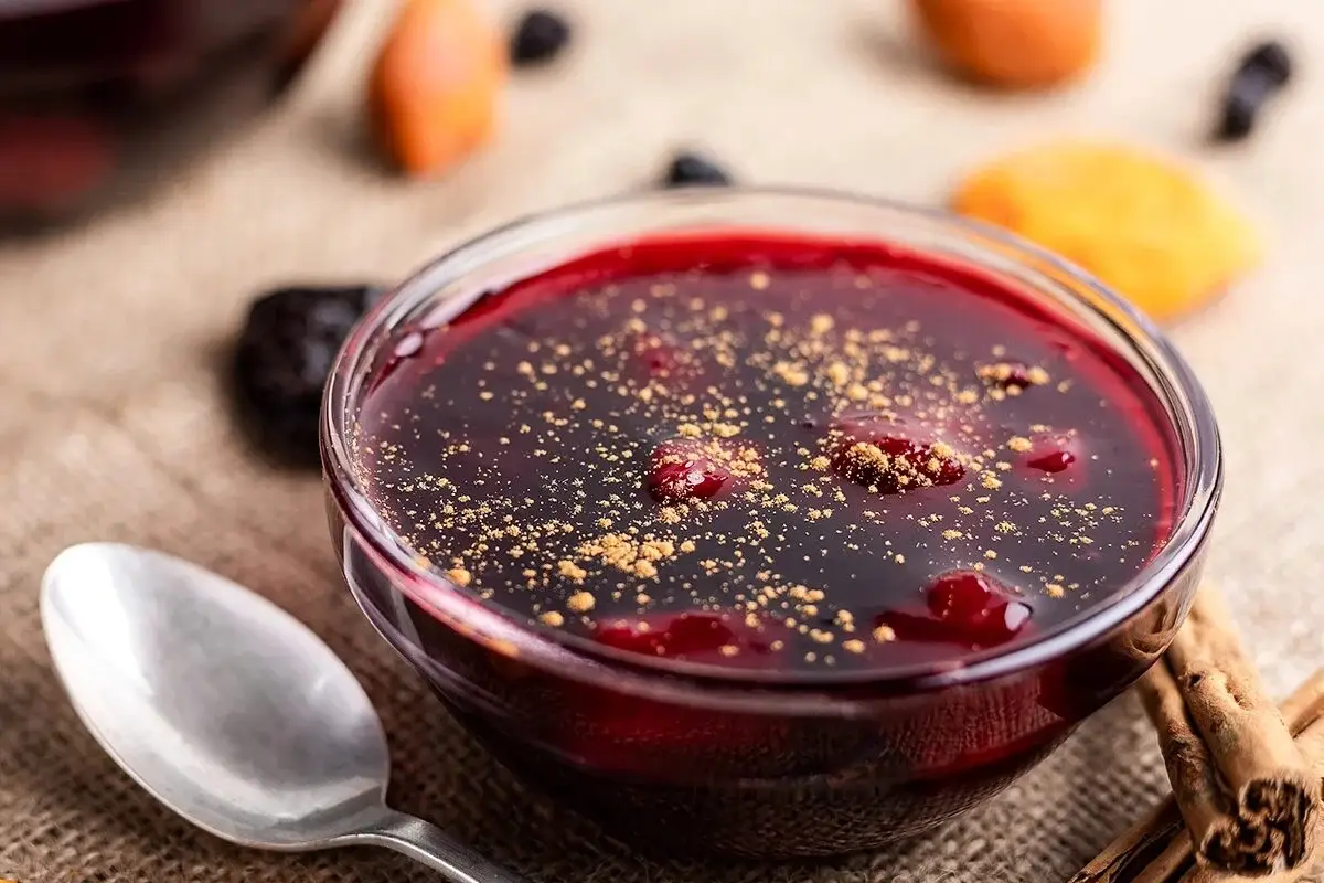 Mazamorra morada en bowl, con canela y frutas, servida junto a una cuchara.