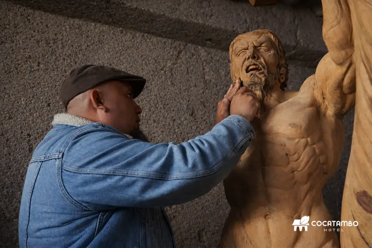 Escultor Michael de Titán trabajando los detalles del rostro de una escultura de madera en un taller.