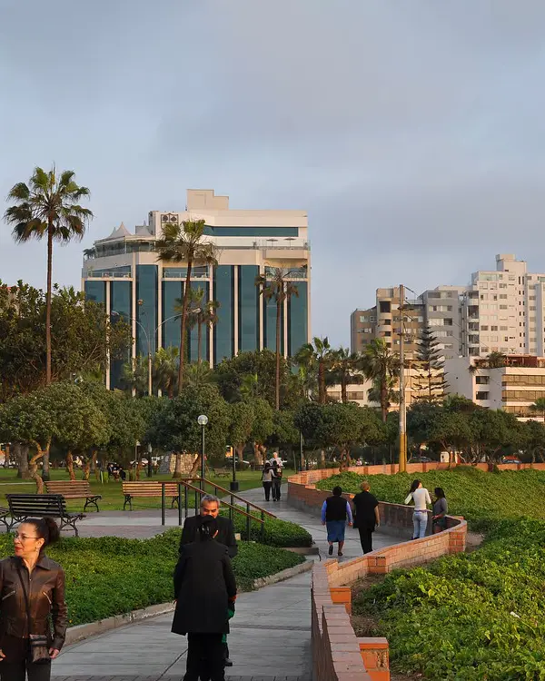Parque urbano con senderos, palmeras y edificios modernos en Miraflores, Lima