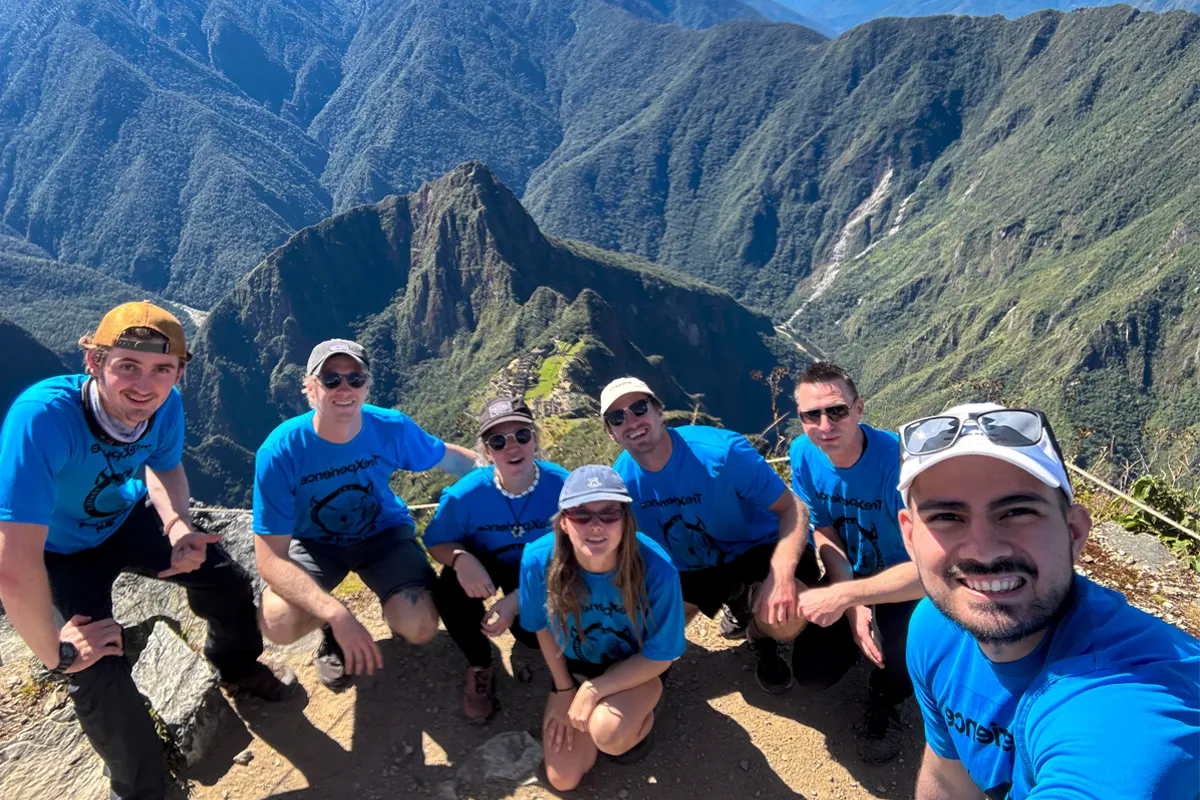 Grupo de viajeros posando en un mirador de la Montaña Machu Picchu con la ciudadela al fondo