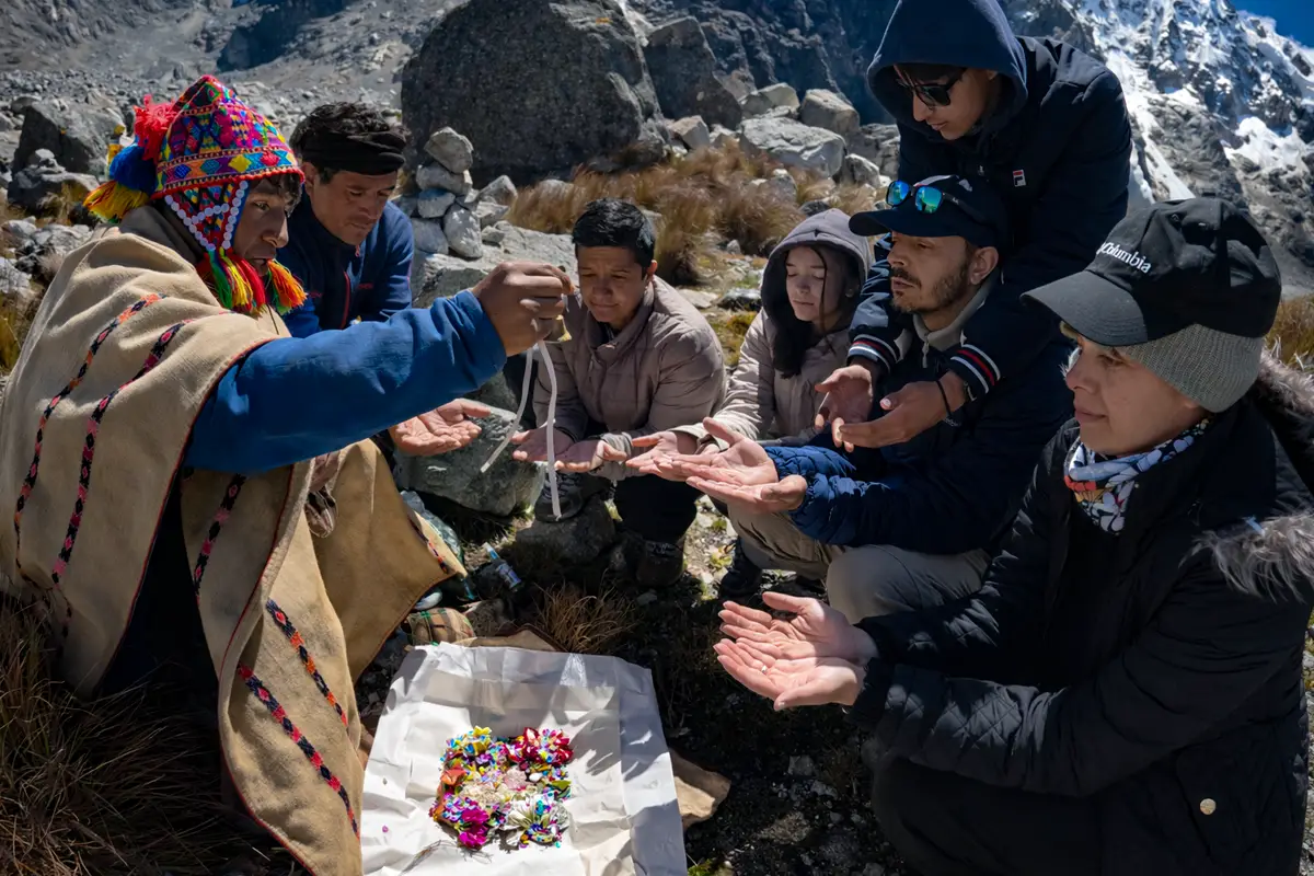Ceremonia de pago a la tierra en alta montaña con un Altomisayoc y un grupo de personas participando en un ritual de ofrenda a la Pachamama