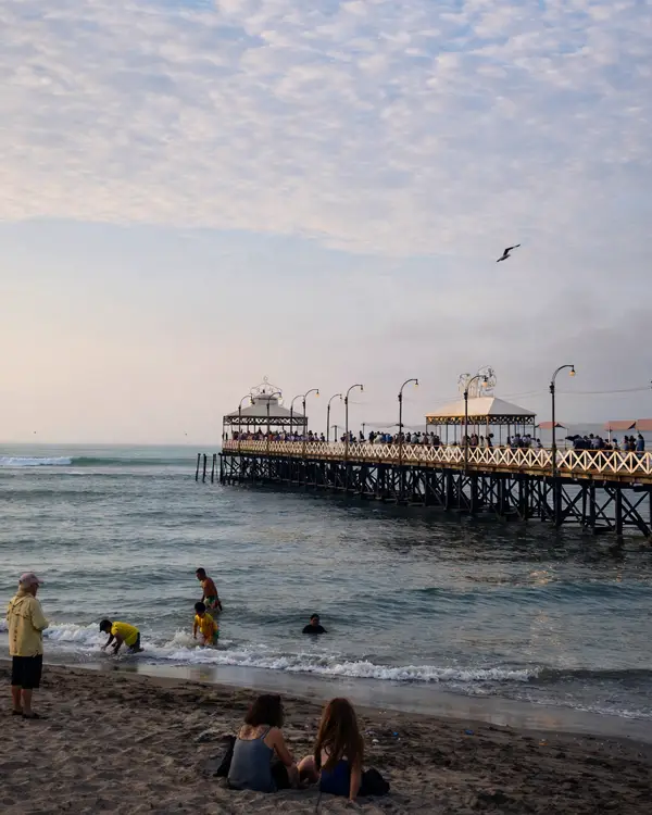 Muelle sobre el mar con visitantes en una playa Huanchaco de la costa peruana