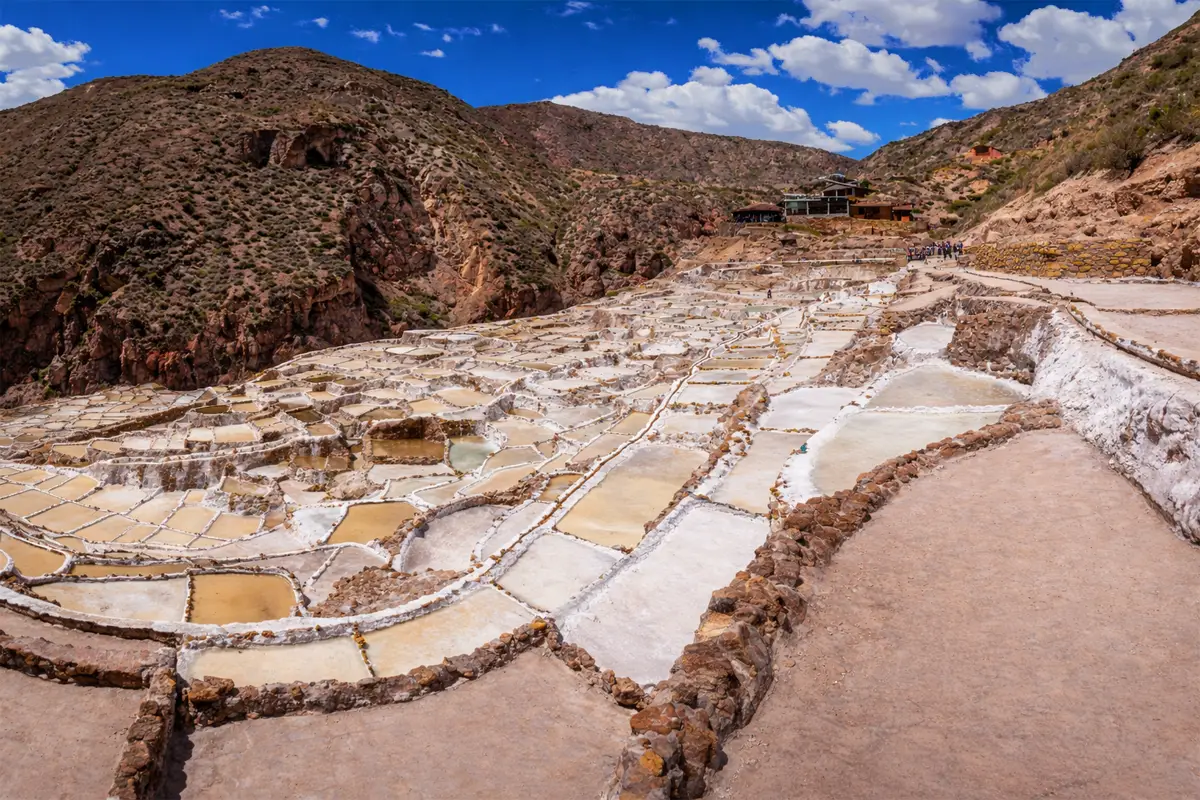 Vista panoramica de las Salineras de Maras con miles de pozas de sal en terrazas y cielo azul en el Valle Sagrado