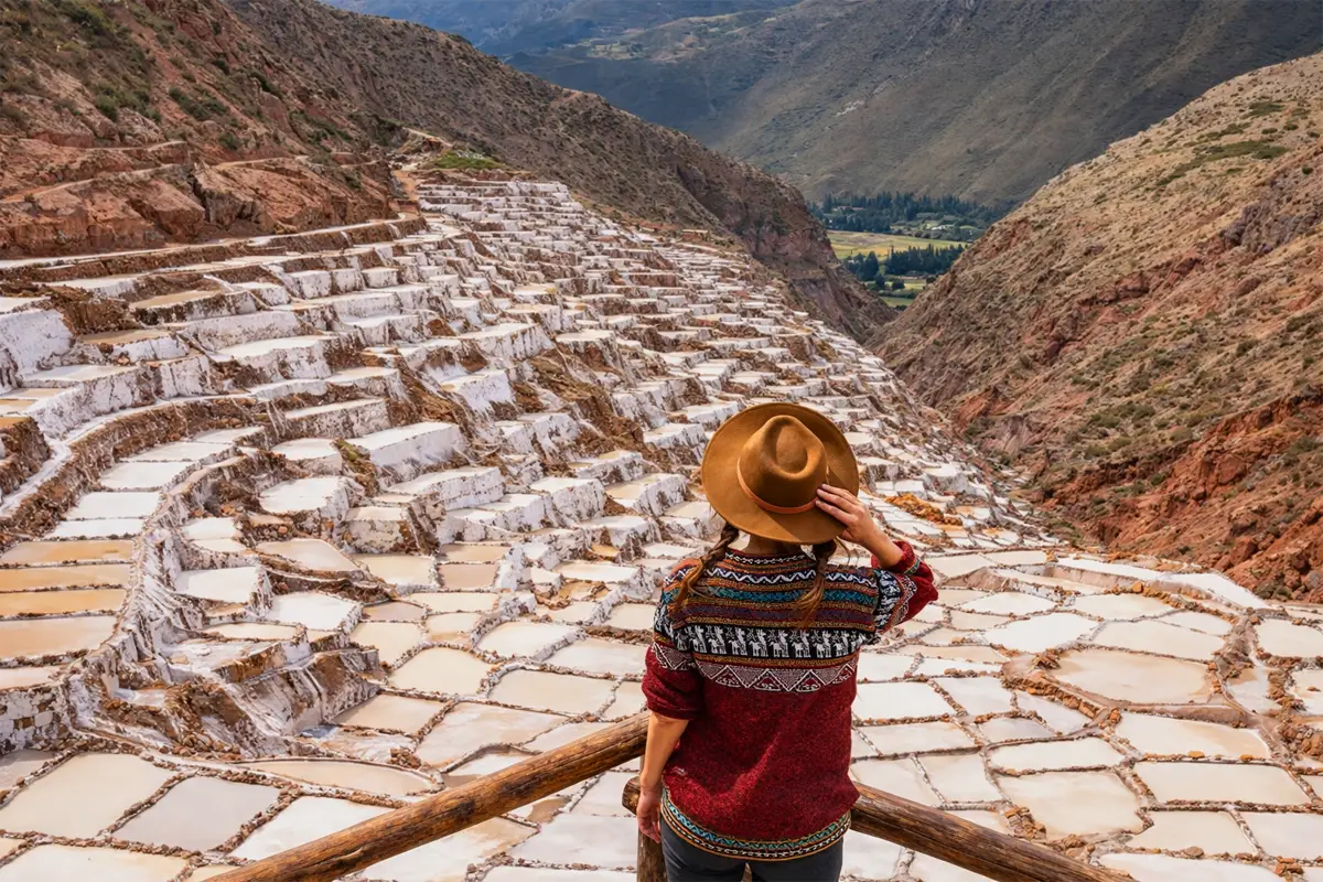 Mirador de las Salineras de Maras con viajera de espaldas y terrazas blancas de sal 