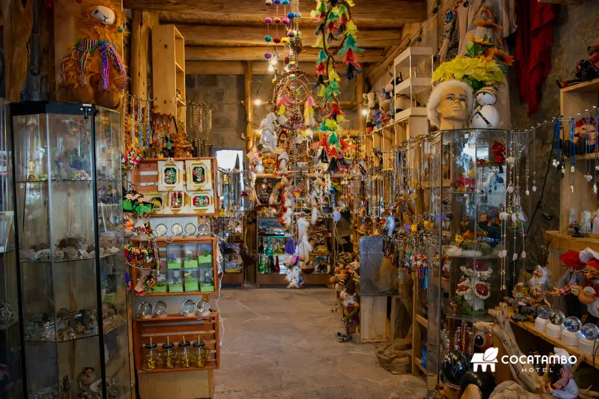 Interior de tienda de recuerdos con artesanías, colgantes, vitrinas y decoración colorida de estilo andino.