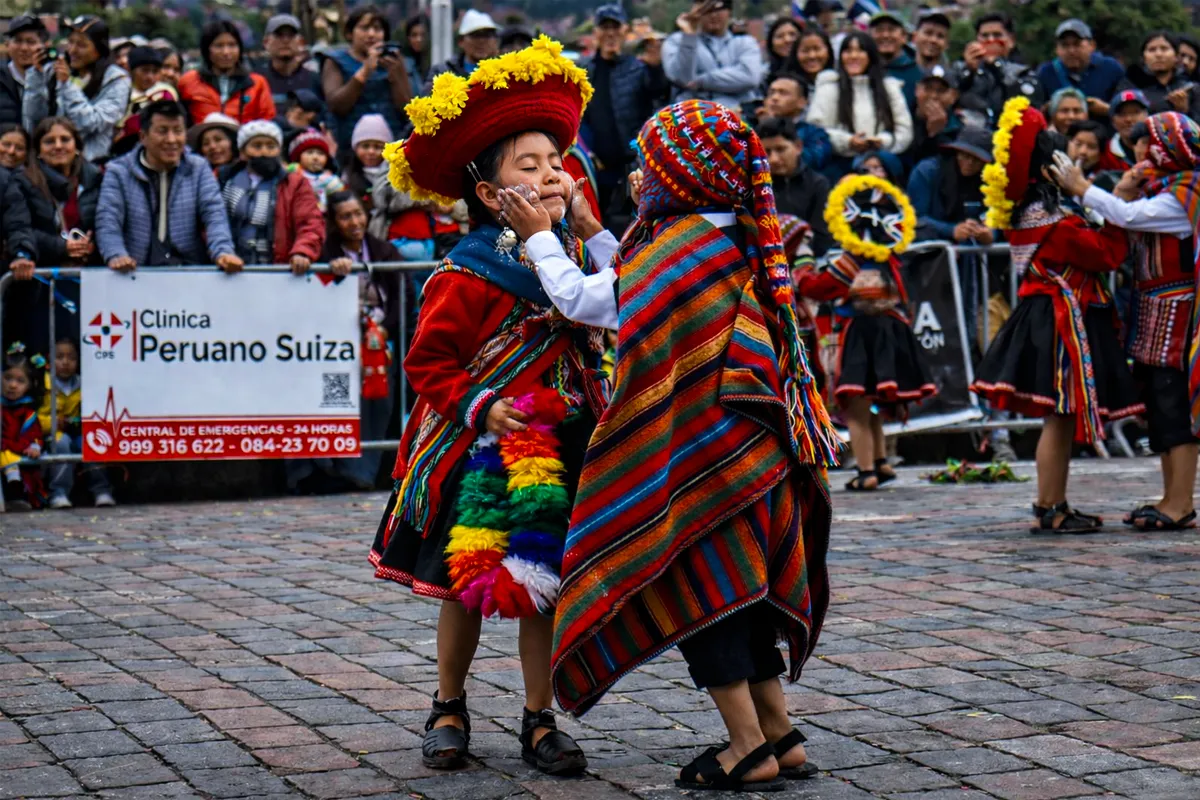 Niños con vestimenta andina tradicional de Chinchero participando en danza cultural frente a espectadores la Plaza Armasm de Cusco .